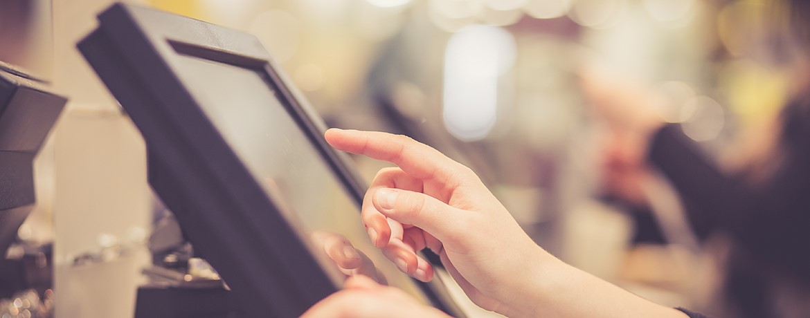 Mitarbeiterin bedient elektronische Kasse. Symbolisch für das Thema Technikfehler bei Datenexport als Steuerrisiko