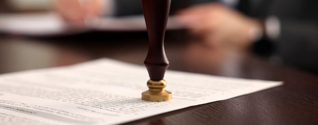 Ein Notar stempelt ein Testament oder eine Urkunde – Symbolbild für rechtlich verbindliche Regelungen im Erbrecht, etwa Teilungsanordnung oder Vorausvermächtnis.