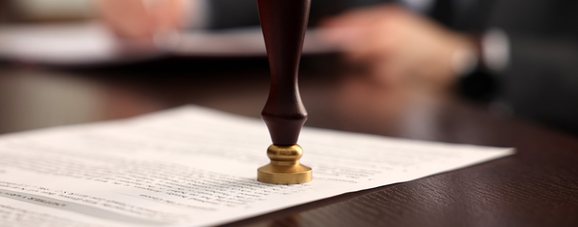 Ein Notar stempelt ein Testament oder eine Urkunde – Symbolbild für rechtlich verbindliche Regelungen im Erbrecht, etwa Teilungsanordnung oder Vorausvermächtnis.