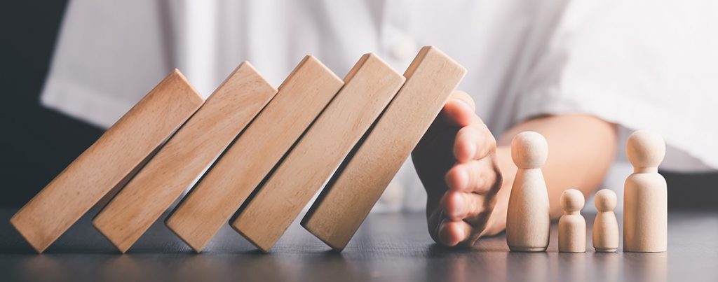 Hand stoppt fallende Holzklötze als Symbol für das Reduzieren von Nachlassverbindlichkeiten und die steueroptimierte Gestaltung einer Erbschaft.