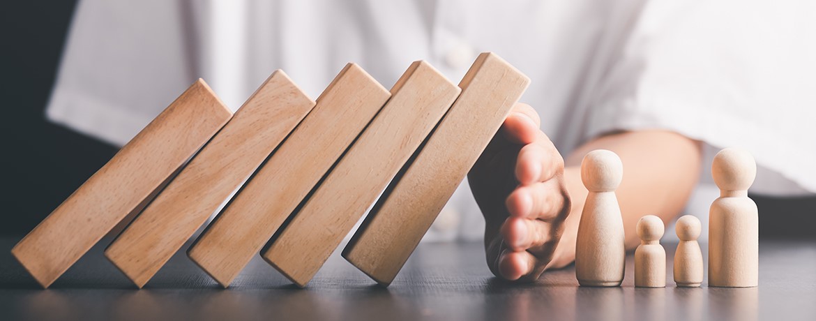 Hand stoppt fallende Holzklötze als Symbol für das Reduzieren von Nachlassverbindlichkeiten und die steueroptimierte Gestaltung einer Erbschaft.