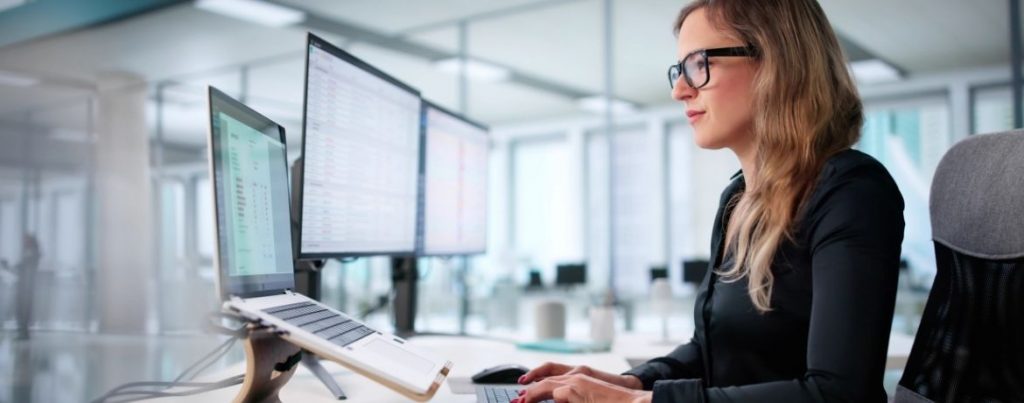 Frau an Bildschirmen bei digitaler Arbeit