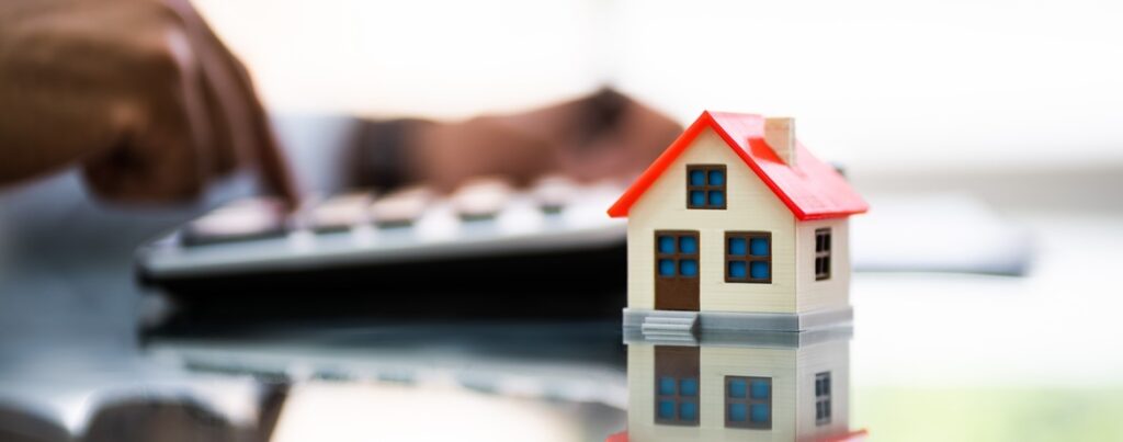 Modellhäuschen vor Hand auf Tastatur - symbolisch für das Thema Familienheim, BFH-Urteil, Erbschaftsteuerbefreiung